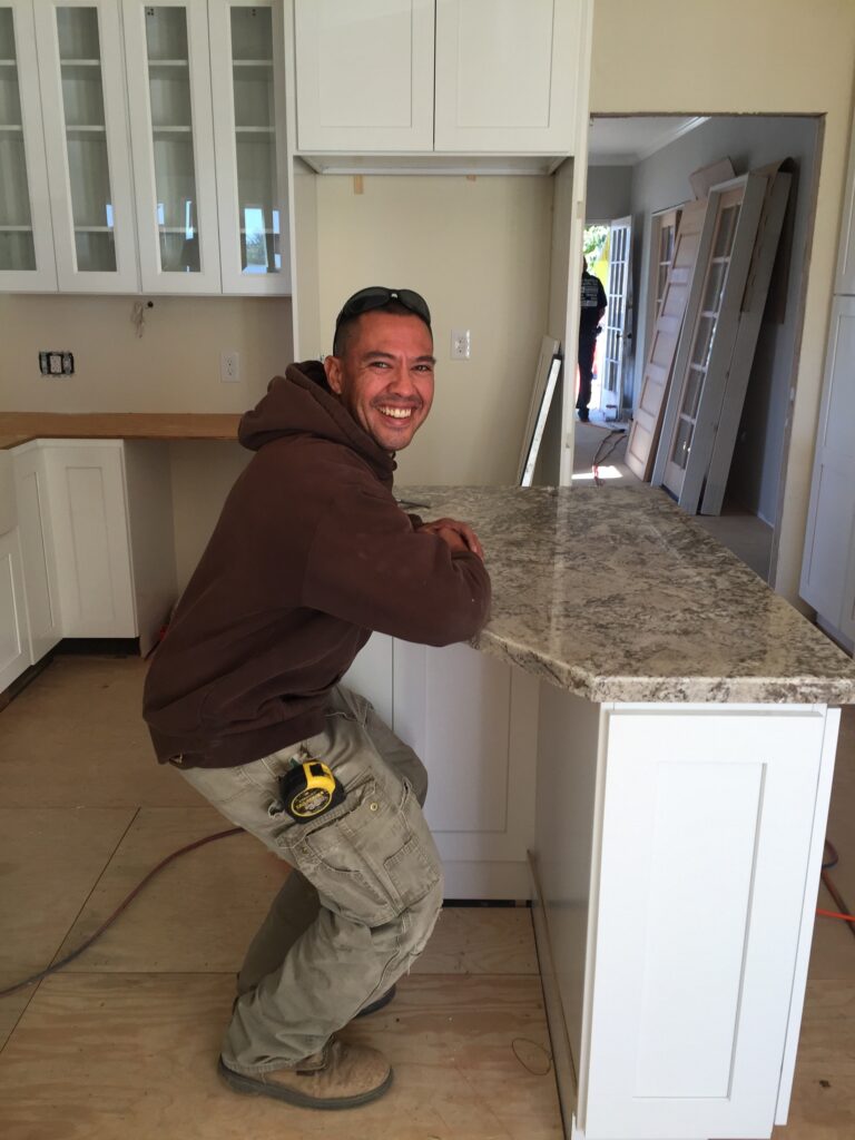 Contractor working on tile countertop smiling