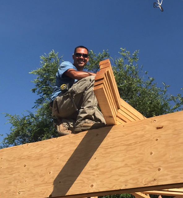 Contractor on roof with wood smiling