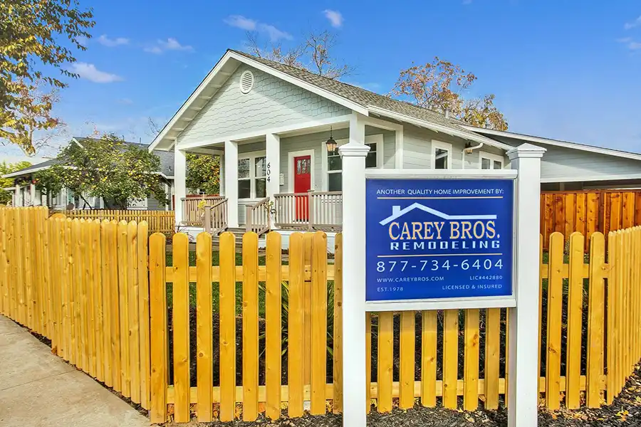 Bungalow in background, natural wood picket fence in foreground, Carey Bros. Remodeling logo signage with phone number as focal point: 877-734-6404