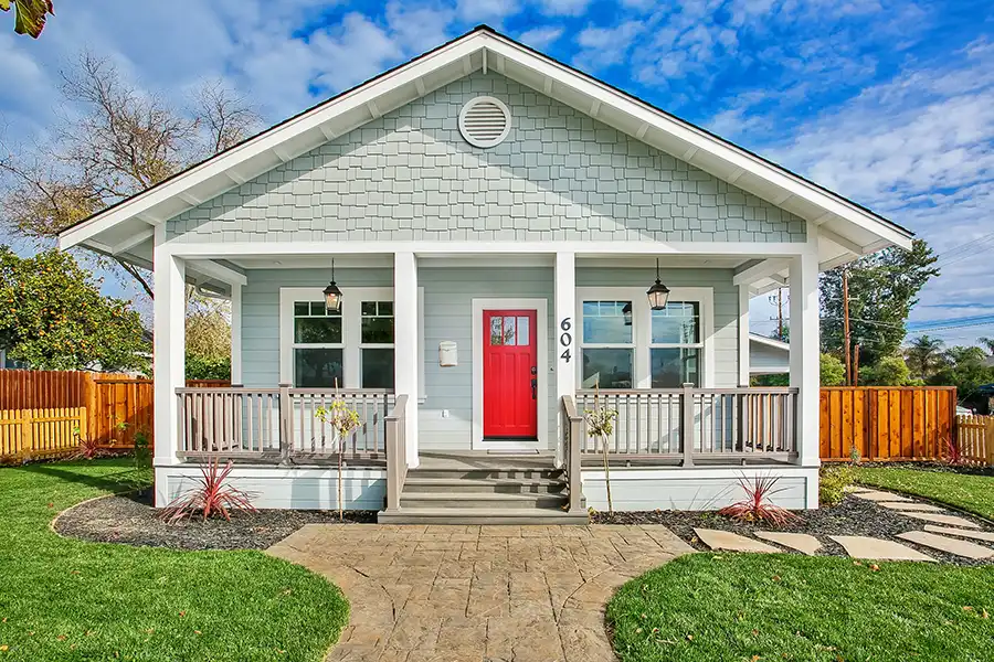 Aqua shingle historic home with fenced porch and red front door