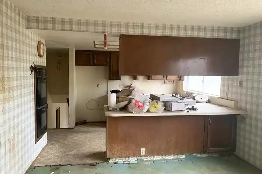 White wood cabinets with brass fixtures, black and white geometric tile flooring, stainless steel appliances with cobalt blue gas stove/oven. Island in center with pot rack above