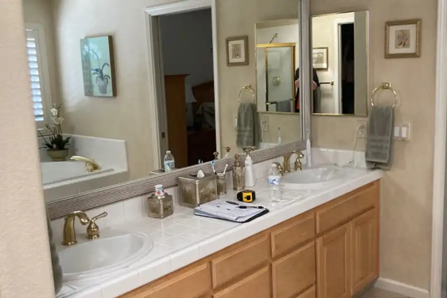 White bathroom with stone floor and clear glass shower and white geometric tub