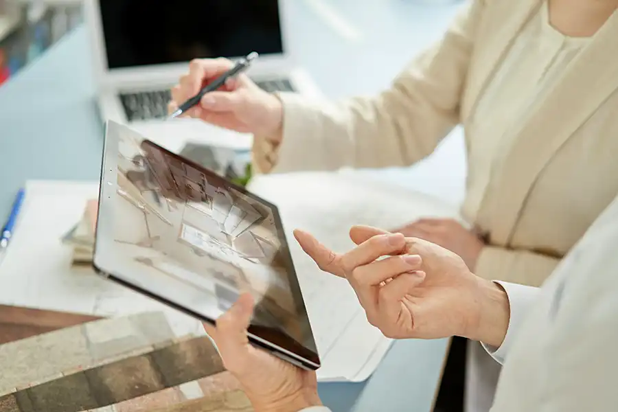 Two people standing with a tablet discussing construction project