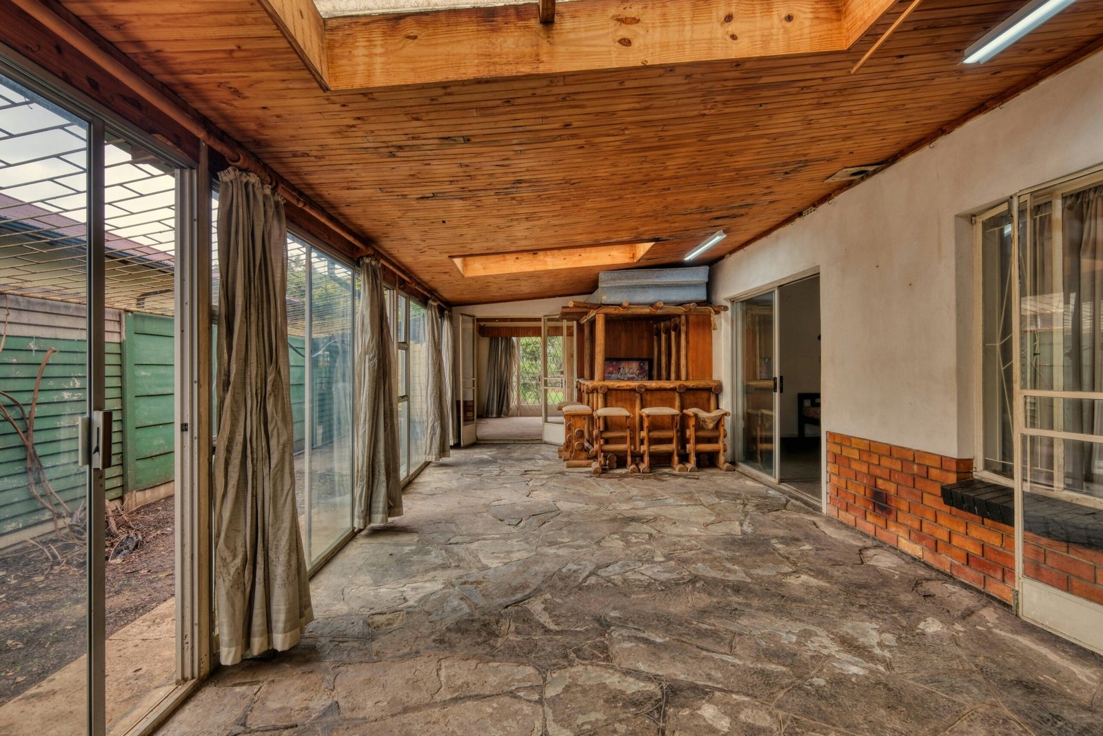 White bathroom with stone floor and clear glass shower and white geometric tub