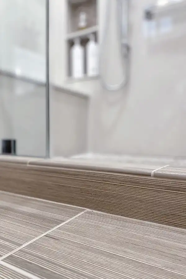 011_5558_Arlene_way16 Creamy almond walls, light-toned wood cabinets with modern hardware, light colored stone countertops with twin sinks, a soaking tub in the corner by a window, with a glass-surround shower in the opposing corner, and wood motif tile on the floors.