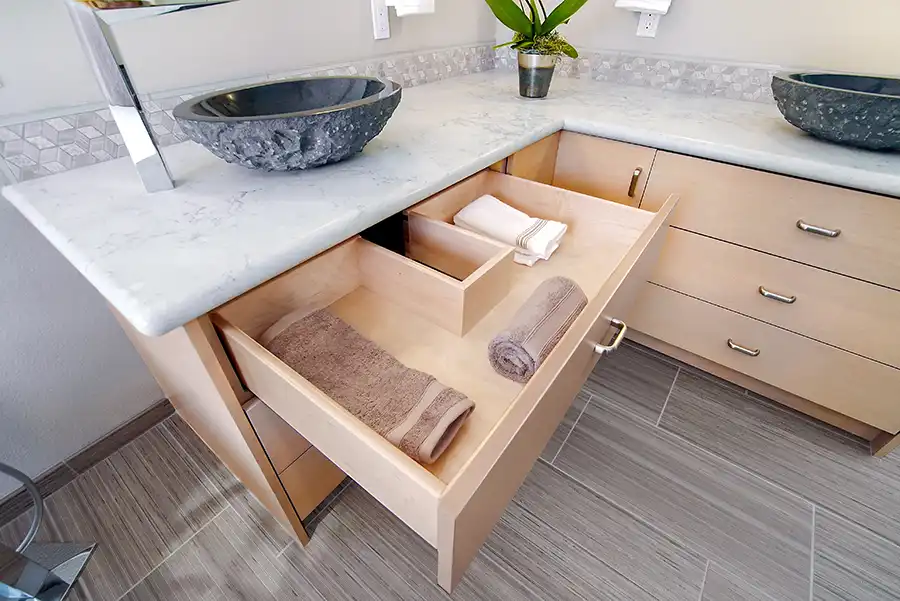 016_5558_Arlene_way9 Creamy almond walls, light-toned wood cabinets with modern hardware, light colored stone countertops with twin sinks, a soaking tub in the corner by a window, with a glass-surround shower in the opposing corner, and wood motif tile on the floors.