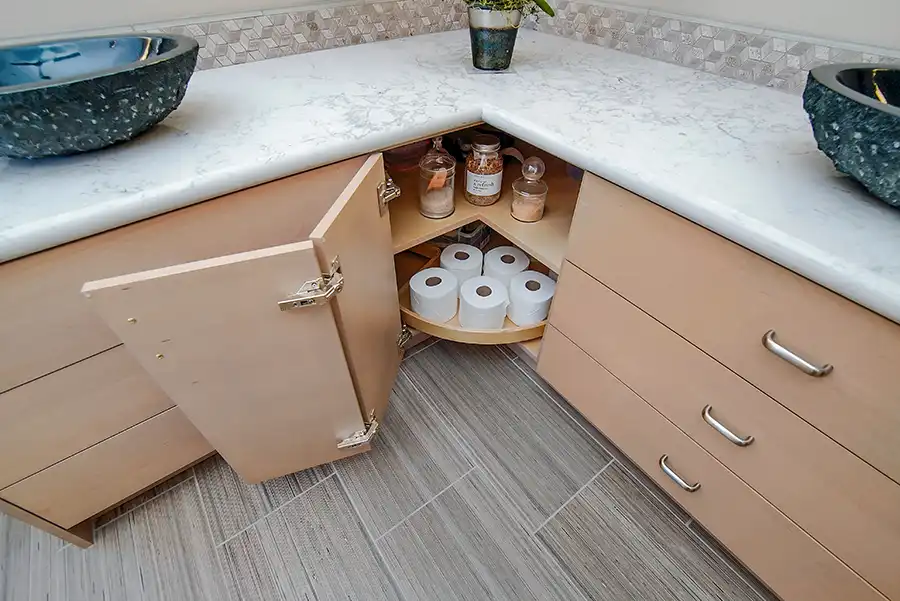 017_5558_Arlene_way10 Creamy almond walls, light-toned wood cabinets with modern hardware, light colored stone countertops with twin sinks, a soaking tub in the corner by a window, with a glass-surround shower in the opposing corner, and wood motif tile on the floors.