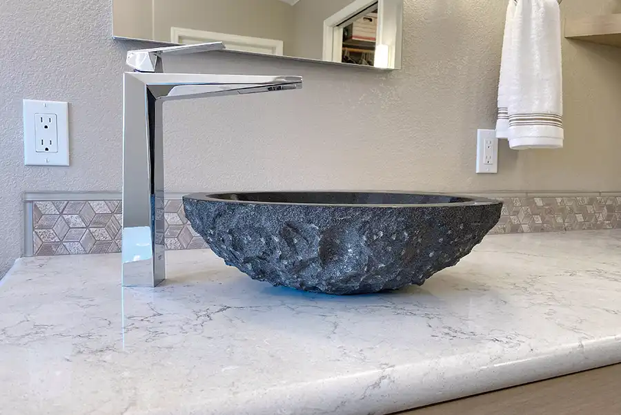 019_5558_Arlene_way22 Creamy almond walls, light-toned wood cabinets with modern hardware, light colored stone countertops with twin sinks, a soaking tub in the corner by a window, with a glass-surround shower in the opposing corner, and wood motif tile on the floors.