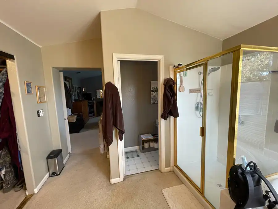 taupe walls, medium-toned wood cabinets, white tile countertops with twin sinks, soaking tub in corner by window, with shower in opposing corner.
