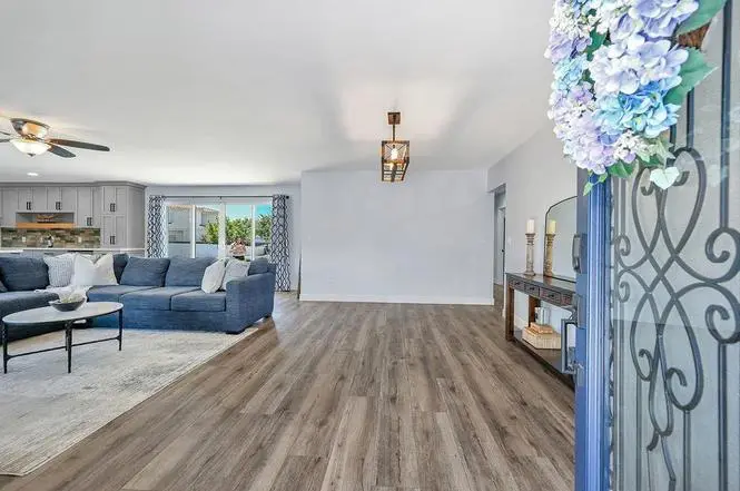 Front entry with a wrought-iron glass door opening onto Kilimanjaro luxury vinyl plank floors, the family room, and the kitchen beyond.
