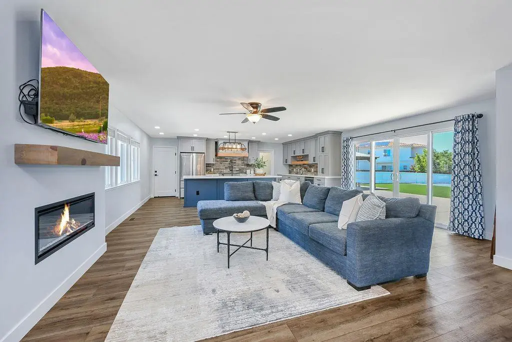 Brentwood family room with a Napoleon Alluravision Slim electric fireplace under a wood mantel shelf, open to the kitchen and patio.