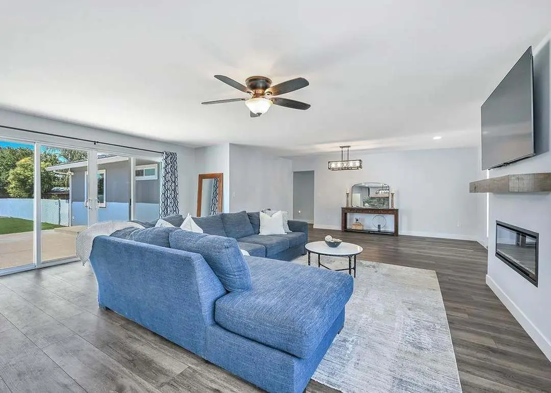 Family room with a 10-foot, four-panel sliding glass door to the backyard, ceiling fan, and wood-look vinyl plank floors.