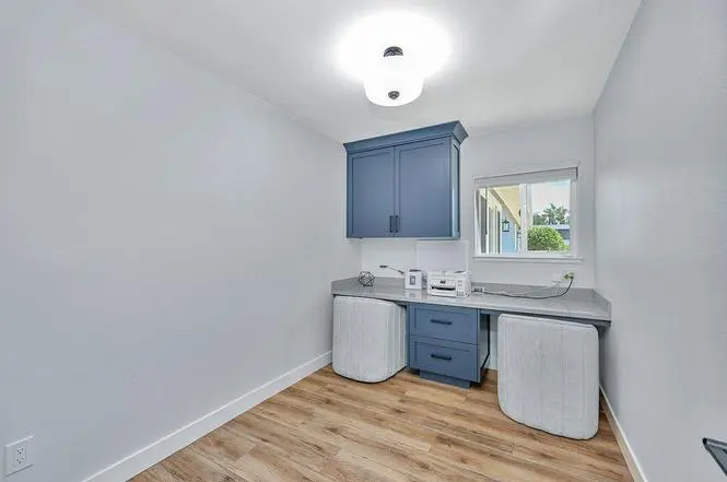 Study in the former kitchen, with blue painted built-in cabinets, a Piedrafina Pebble Beach desktop, and a window.