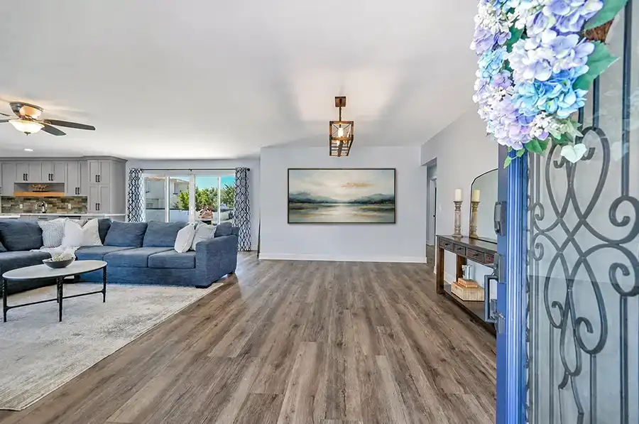 Front entry with a wrought-iron glass door opening onto Kilimanjaro luxury vinyl plank floors, the family room, and the kitchen beyond.
