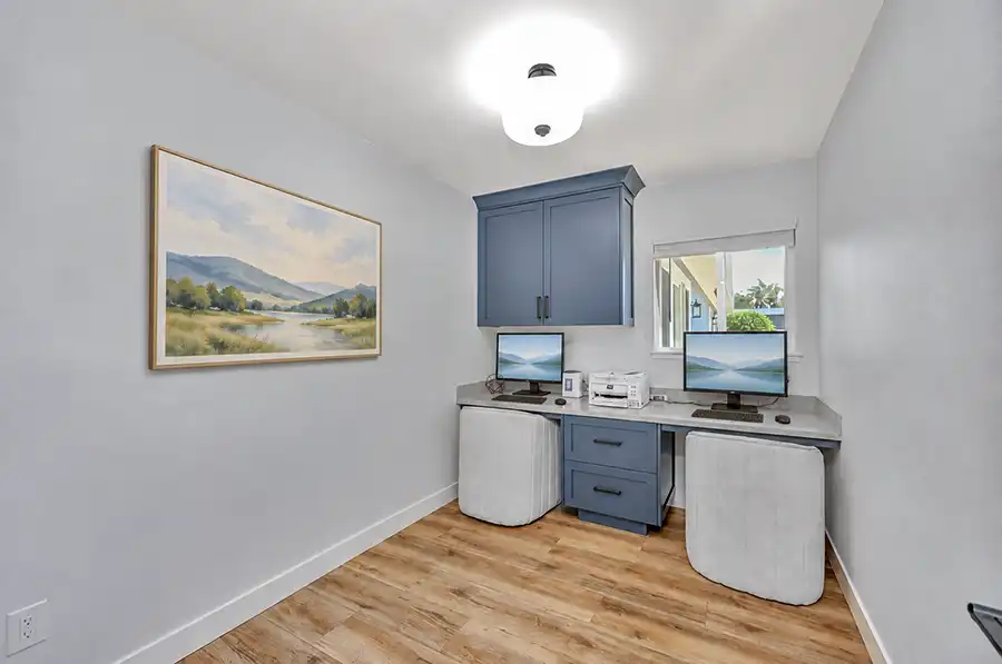 Study in the former kitchen, with blue painted built-in cabinets, a Piedrafina Pebble Beach desktop, and a window.